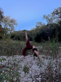 a woman doing a handstand in the middle of a field